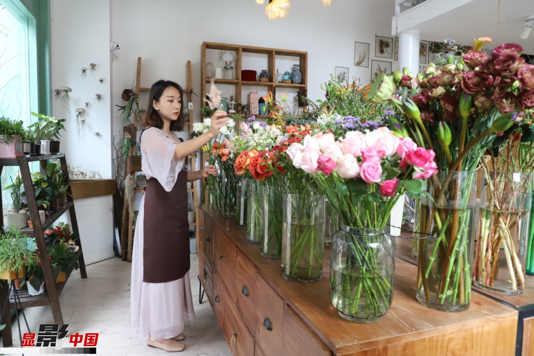 王黎媛是一名河南姑娘，在昆明念完大學(xué)后，就再也舍不下春城的藍(lán)天陽(yáng)光、青山碧水，更舍不下這里的四時(shí)繁花，于是就干脆留了下來(lái)，成了一名媒體人。2017年的時(shí)候又毅然辭去工作，創(chuàng)業(yè)開(kāi)起了花店，成了都市里的一名“花房姑娘”。圖為王黎媛在自己的花店中整理鮮花。新華網(wǎng) 周亞平/攝 念新洪/文